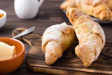 Fresh crispy croissants on a wooden board on the table. Brunch and coffee break. Close-up