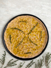 Unbaked focaccia round flat bread. Homemade pastry food with thyme herbs and salt top view.