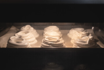 Meringue cake on the baking sheet in the oven close up background.