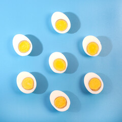 Hard boiled egg halves in a circle on a blue background, Contemporary food art flat lay 