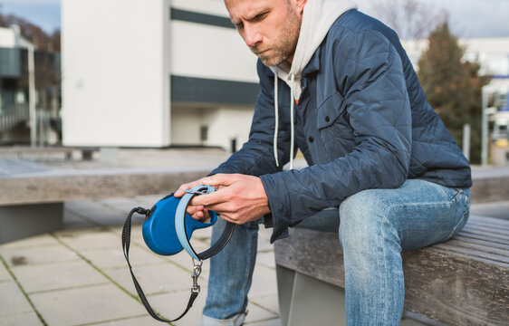 Broken with grief man dog owner is grieving sitting on a bench with the lovely pet collar and deep weeping about animal loss. Home pets relatives and love concept.