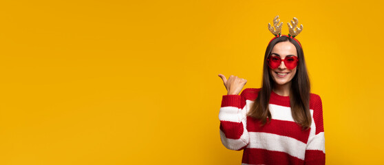 Banner wide photo of an attractive excited smiling young girl in Christmas reindeer antlers and...