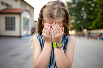 Little school girl hiding her face, feeling sad. Kids bullying concept