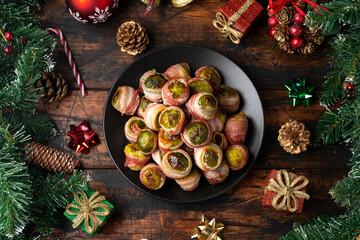 Christmas Streaky bacon wrapped Brussel sprouts with decoration, gifts, green tree branch on wooden...