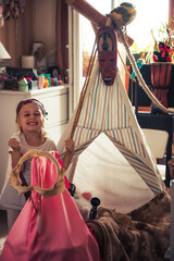 Happy mischievous small child girl playing pirates in her children room with built pirate’s ship...
