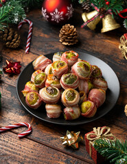 Obraz na płótnie Canvas Christmas Streaky bacon wrapped Brussel sprouts with decoration, gifts, green tree branch on wooden rustic table