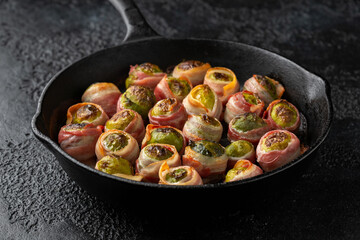 Streaky bacon wrapped Brussel sprouts in cast iron pan