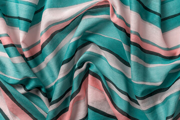 Draped striped fabric of teal and orange colors background. Texture of folded thin cotton cloth...