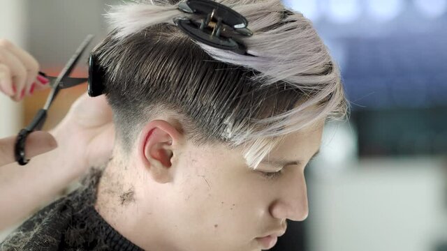 Cutting a young person's hair with scissors at home. High quality 4k footage