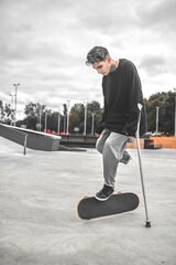 Guy leaning on crutches and touching skateboard with foot