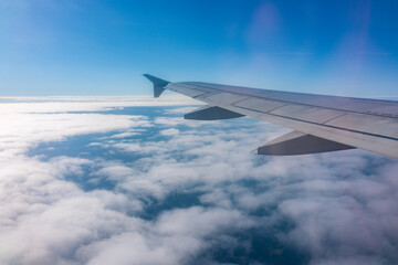 View from the airplane window at a beautiful cloudy sky and the airplane wing