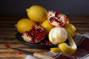 Still life with lemons and pomegranate on a plate.
