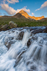 Mountain river in the Italian Alps with fiery peaks in the background, Stelvio National Park, Lombardy, Italy