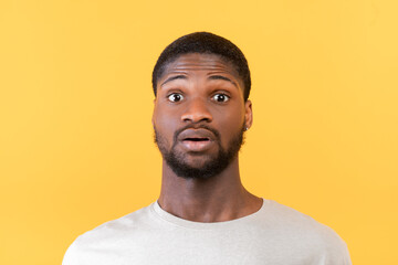 Obraz premium Unbelievable news. Portrait of surprised black guy opening his eyes in shock, looking at camera on yellow background