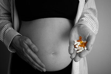 Pregnant woman holding pills on her hand. The concept of taking antidepressants and drugs during...