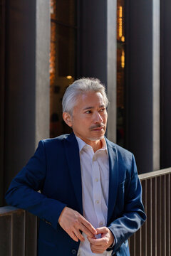 Pensive Japanese Businessman Near Fence