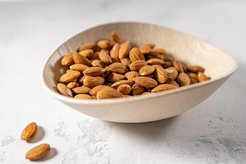 Almond nut seeds in plate on the table, white background with selective focus