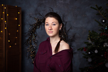 Fototapeta premium Woman in pajamas near Christmas tree and gifts. Dark blue concept