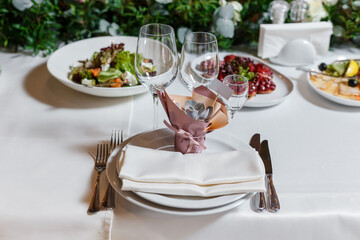 Gift for guests at the wedding - blank invite guest card and cute succulent. Party table setting with napkin, wineglasses, dish. Reception decor in restorant