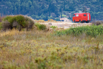 A vibrant red van carrying bicycles in the outdoors against some foliage