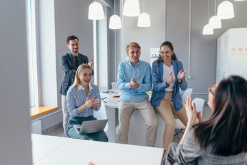 Businessoman receives approval and applause from her colleagues in an office meeting.