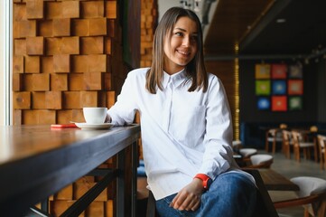 pretty young woman sitting in the cafe with a cup of tea