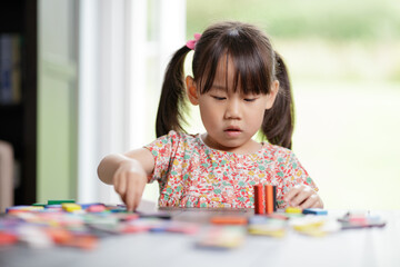 young girl playing domino blocks at home