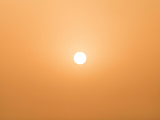 View to the sun during the middle of day in desert. Arabian orange sky.