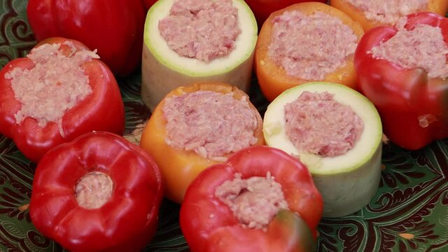 People hands are preparing food. Peppers, tomatoes, zucchini and grape leaves stuffed with minced meat.
