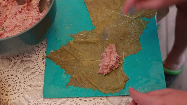 People cook dolma food.
Grape leaves stuffed with minced meat.