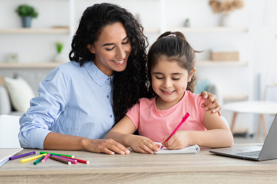 Caring arab mother helping her little daughter with homework and study