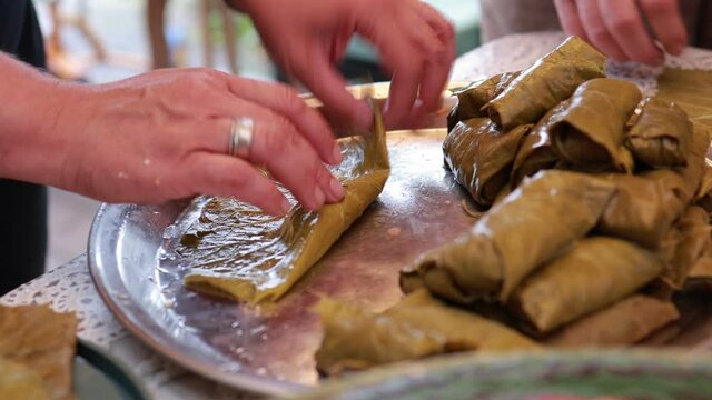 People cook dolma food.
Grape leaves stuffed with minced meat.