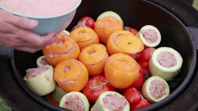 People hands are preparing food. Peppers, tomatoes, zucchini and grape leaves stuffed with minced meat.