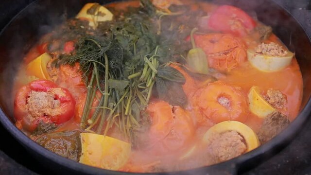 People hands are preparing food. Peppers, tomatoes, zucchini and grape leaves stuffed with minced meat.