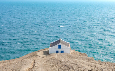 Simple small little house on the edge of a cliff overlooking the sea