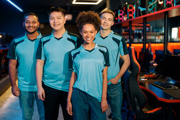 Team of four young multiracial professional cybersport gamers happy with their game while standing...