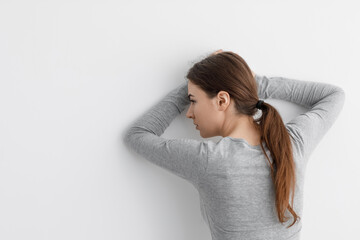Fototapeta premium Unhappy worried caucasian millennial lady suffering from depression, leaning against white wall at home