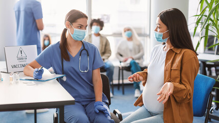 Doctor Talking With Pregnant Woman Before Vaccination In Hospital