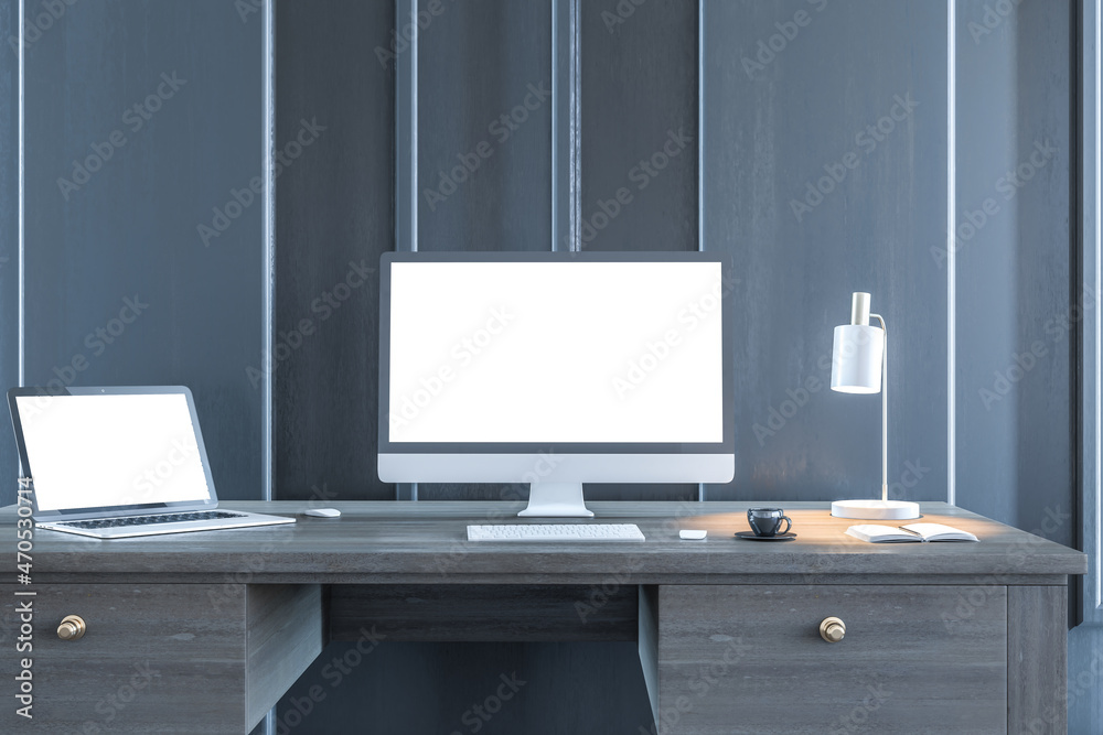 Poster modern designer desktop with empty white computer and laptop screens in wooden interior at night. wo