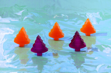 Three orange and two purple Christmas trees on a holographic background. Retro futuristic creative concept for Christmas or New Year card or banner or advertisement.