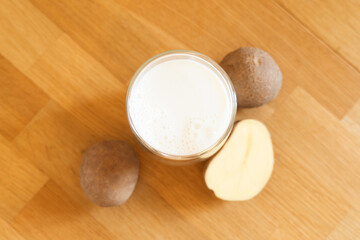 Potato milk photo on wooden background. Glass of alternative milk. Plant based vegetarian beverage. Lactose free drink