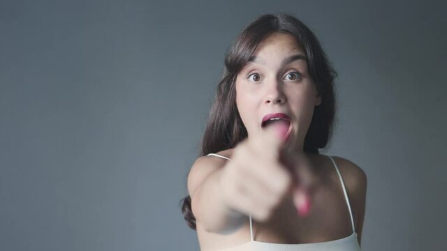 expressive caucasian brunette female 20 saying wow wondering on grey background copy space. portrait young woman chocked surprised mouth opened hands cheeks big eyes wide. emotions advertising concept