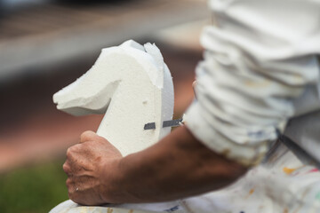 Person making a figure of a horse from a piece of polystyrene