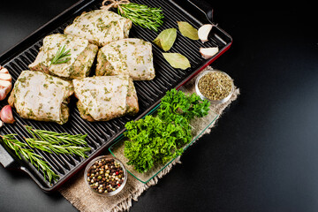 Chicken thighs with spices, garlic.Copy space.Close-up, top view.Raw chicken thighs marinated in herbal sauce on a dark background with fresh rosemary, spices.Raw Meat Chicken.