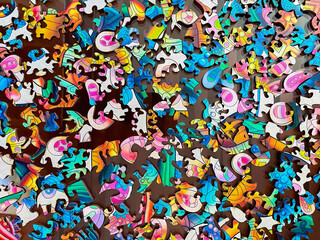 top view of a multitude of colored pieces of a wooden puzzle, with the shape of the pieces different from the usual