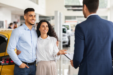 Fototapeta na wymiar Happy arabic family buying new car, talking to sales manager