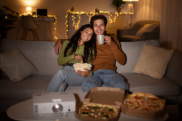 Couple Watching Film On Cinema Projector Eating Pizza At Home