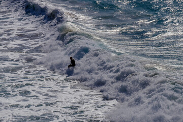 View on the ocean and an little figure of a surfer in the waves.