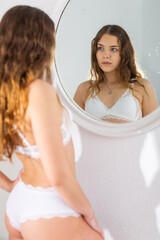 Obraz na płótnie Canvas Girl in lingerie looks at herself in the mirror