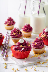 Homemade red cupcakes with golden sprinkles and cream.